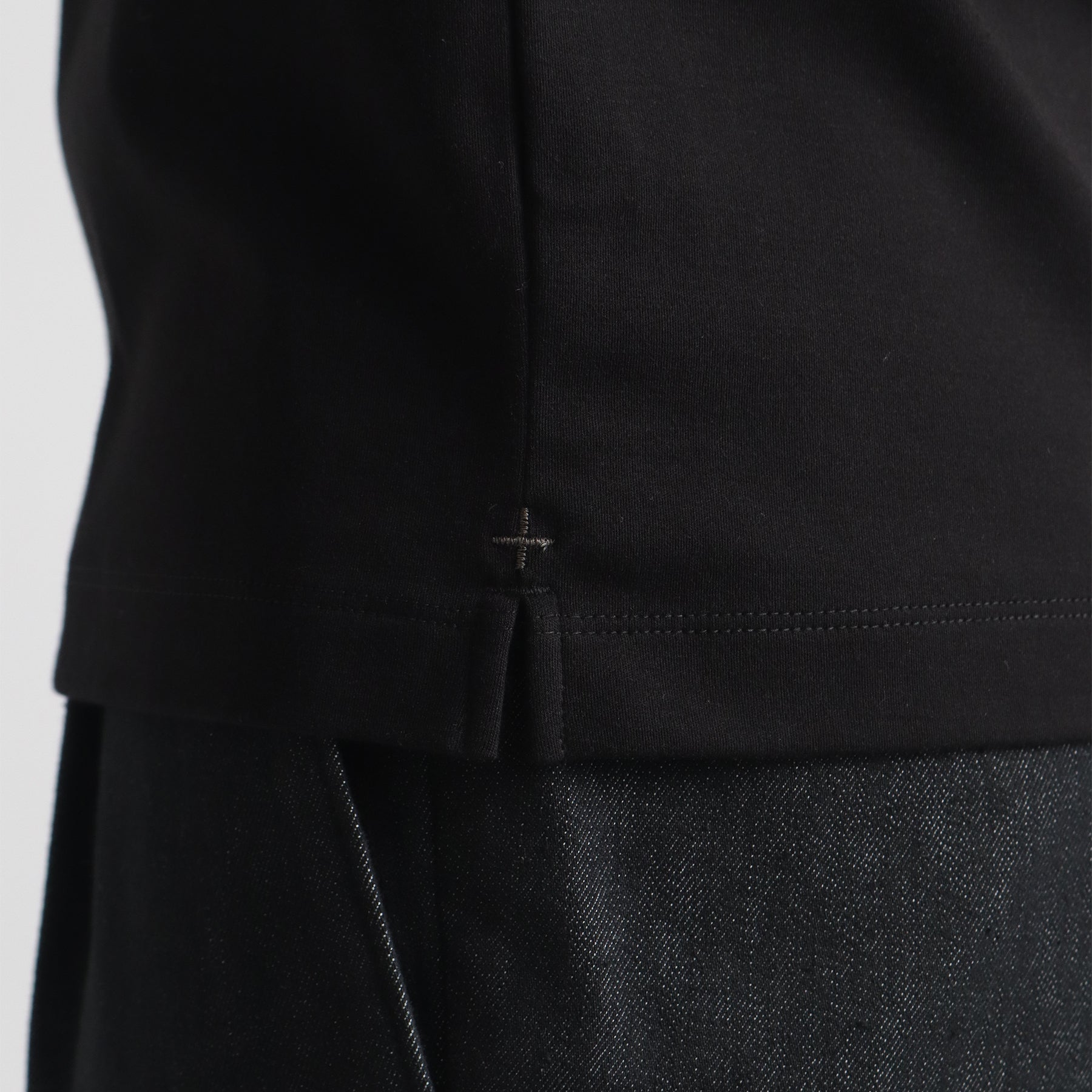 スビンプラチナムスムースヘンリーネックTシャツブラックの裾を写したメンズ着用画像