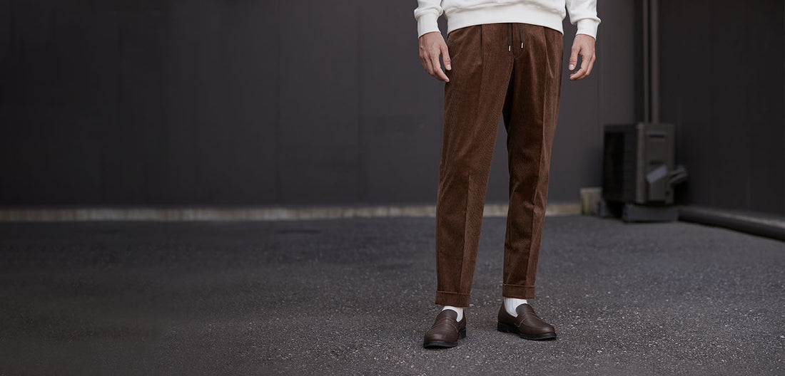 茶色のコーデュロイパンツをはいたモデル
