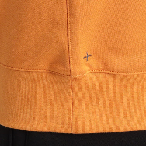 スヴィンプラチナム裏毛スウェットシャツアンバーオレンジの裾を写したメンズ着用画像